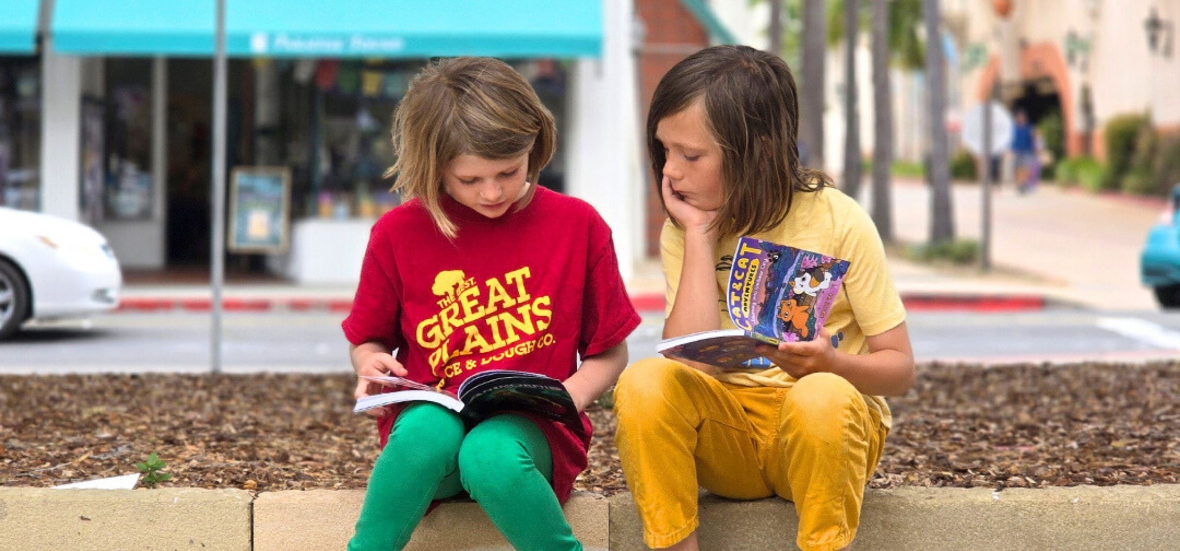 Two children reading on the library plaza