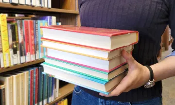 woman holding stack of books