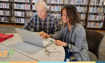 tutor sitting at table with learner at the library