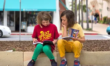 two kids reading at the library plaza