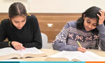 Two teens study at desk in the library