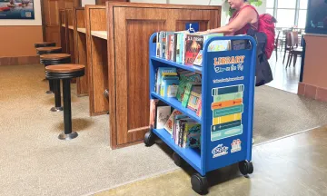 A woman browses the Library on the Fly bookshelf