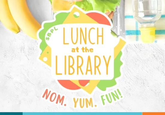 A colorful sandwich sits on a lunch table, with the text "Lunch at the Library" located on the bread and "Nom. Yum. Fun!" below.