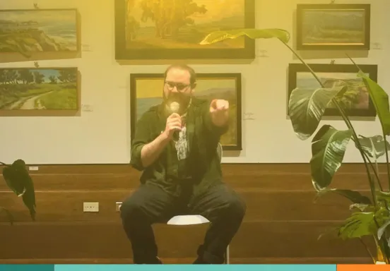 a person sits on a chair with a microphone 