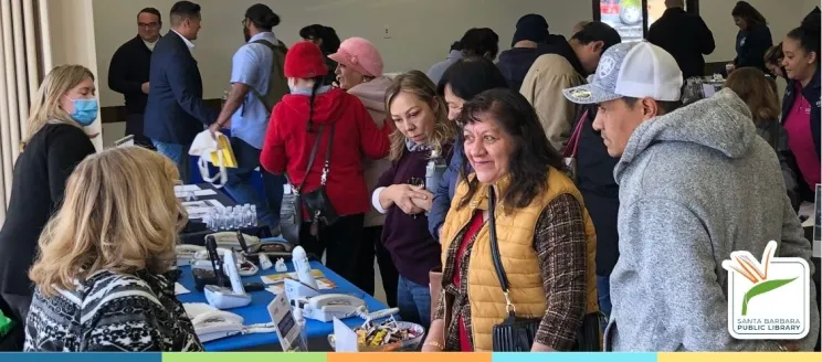 people standing around a table, speaking to staff