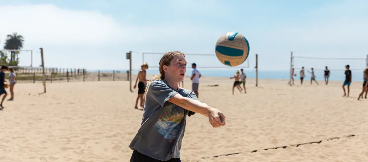 Beach volleyball camper bumps a volleyball at the East Beach courts