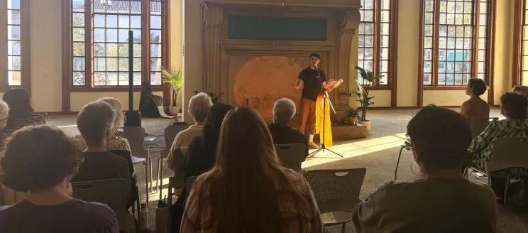A patron reads poetry to a seated crowd in the library
