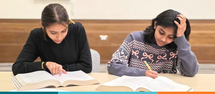 Two teens study at desk in the library