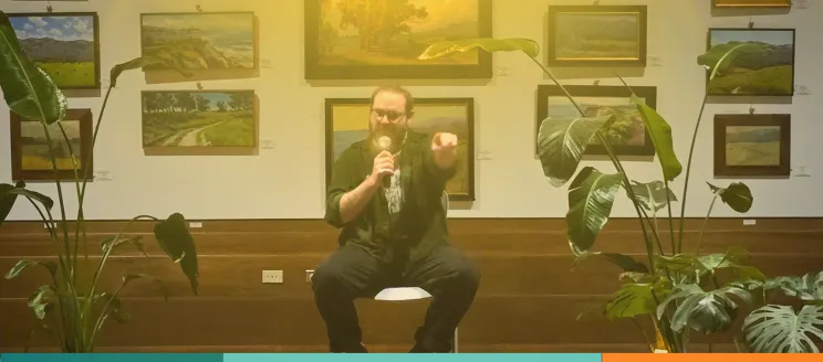 a person sits on a chair with a microphone 