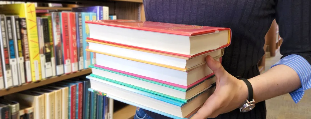 woman holding stack of books