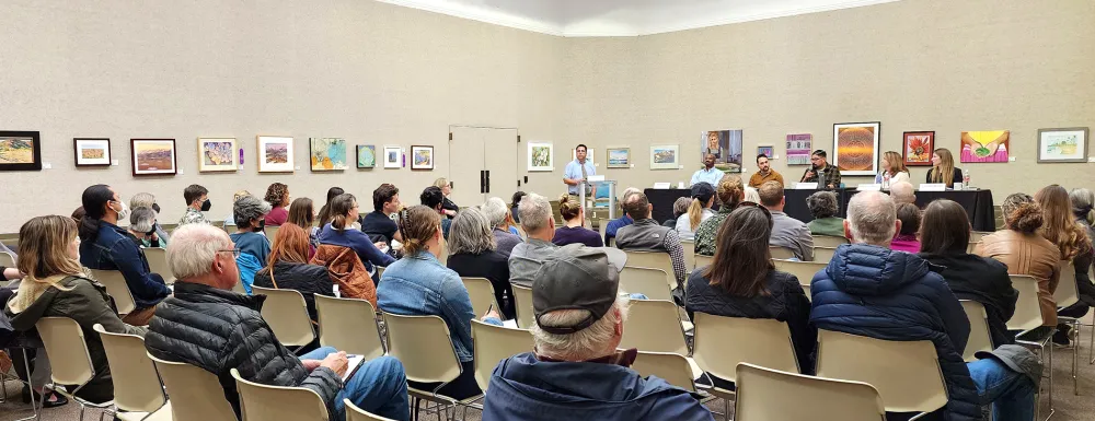 a large crowd listens to a speaker in Faulkner gallery