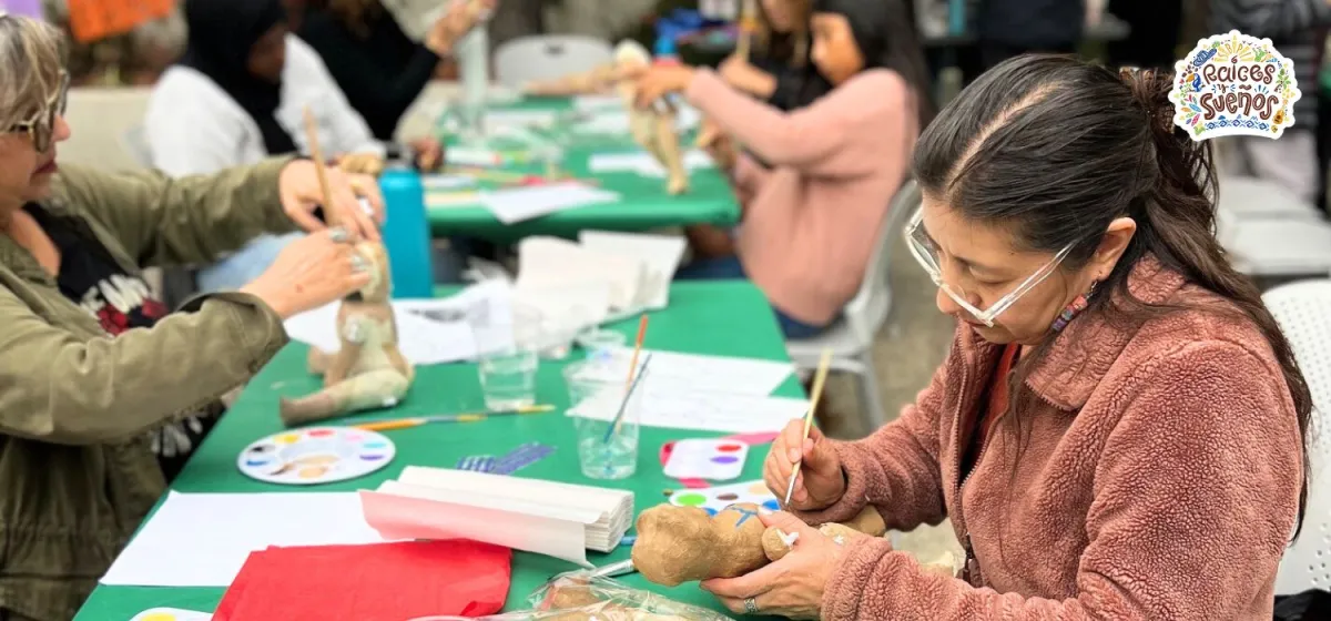 woman holds paper mache doll and paints details 