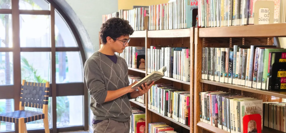 Teen Reading a book in front of shelf